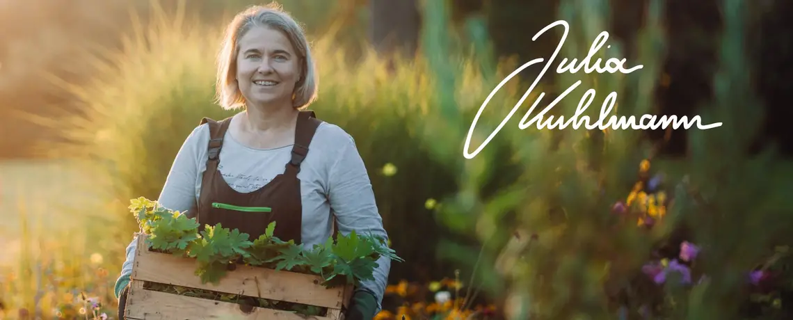 Julia Kuhlmann in Ihrem Garten mit einer Kiste voller Pflanze in den Armen