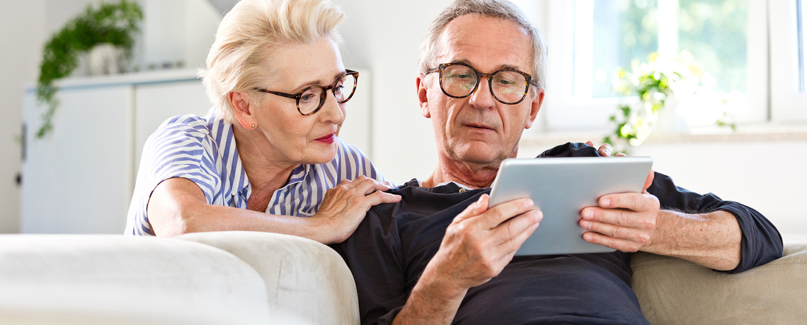 Frau und Mann lesen gemeinsam die digitale Tageszeitung auf einem Tablet